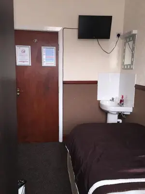 a bedroom with a bed and a sink and a door at The Trentham Hotel in Blackpool