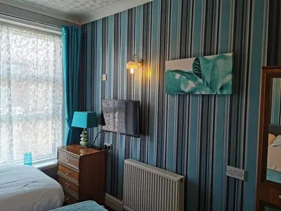 a bedroom with a bed and a tv on a striped wall at The Trafalgar in Blackpool