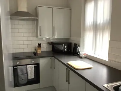 a kitchen with white cabinets and a black counter top at Jeffersons Hotel & Serviced Apartments in Barrow in Furness