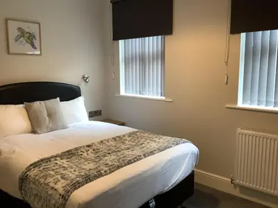 a bedroom with a bed and two windows at Jeffersons Hotel & Serviced Apartments in Barrow in Furness
