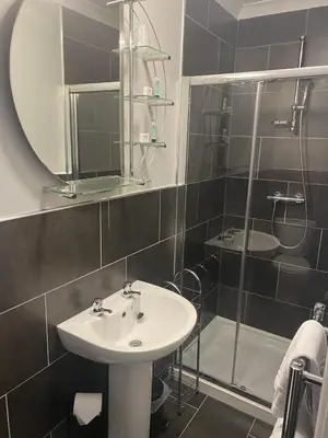 a bathroom with a sink and a shower with a mirror at Jeffersons Hotel & Serviced Apartments in Barrow in Furness