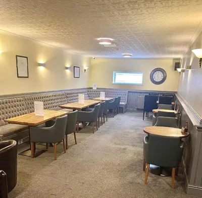 a dining room with tables and chairs and a clock at Jeffersons Hotel & Serviced Apartments in Barrow in Furness