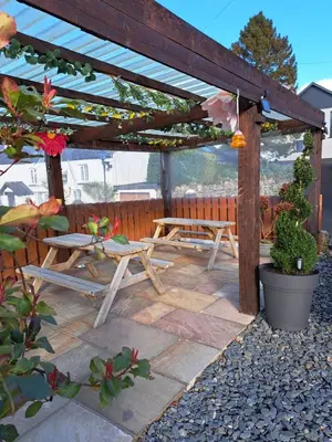 a wooden pergola with a picnic table and a bench at The Ship Inn in Bardsea