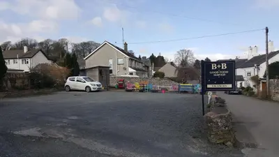 a white car parked on a street with a sign at The Ship Inn in Bardsea