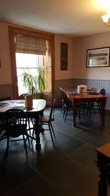 a dining room with tables and chairs and a window at The Ship Inn in Bardsea