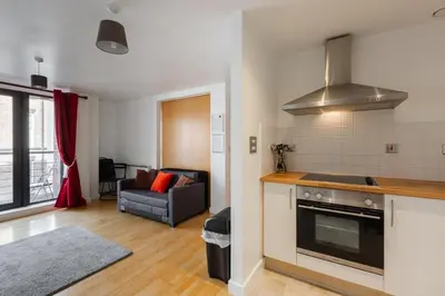 a kitchen and living room with a stove and a couch at Liverpool City Centre Apartments - East Village in Liverpool