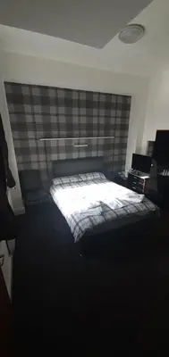 a bedroom with a bed and a wall at The Lodge Guest Accommodation in Barrow in Furness