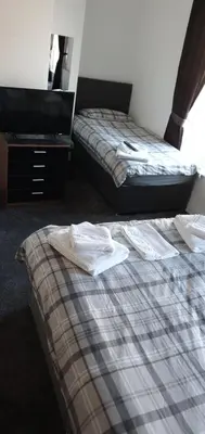 a room with two beds and a dresser at The Lodge Guest Accommodation in Barrow in Furness