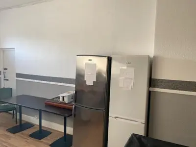 a refrigerator and a table in a room at The Lodge Guest Accommodation in Barrow in Furness