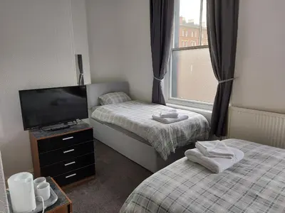 a small room with two beds and a television at The Lodge Guest Accommodation in Barrow in Furness