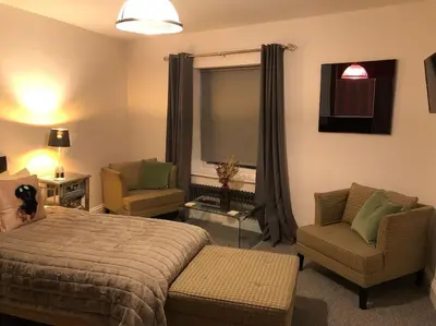 a bedroom with a bed and two chairs and a window at Ten Streets Bed & Breakfast in Liverpool