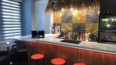a bar with orange stools in a room at Tropics Beach Hotel in Blackpool
