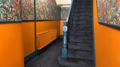 an orange hallway with stairs and a painting on the wall at Tropics Beach Hotel in Blackpool