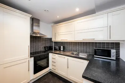 a kitchen with white cabinets and a black counter top at Staycity Aparthotels Liverpool City Centre in Liverpool