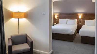 a hotel room with two beds and a chair at Holiday Inn Liverpool City Centre by IHG in Liverpool