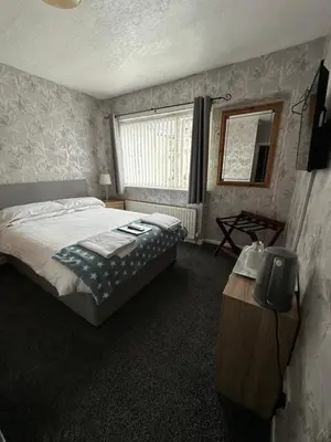 a bedroom with a bed and a table and a window at The Villa Hotel in Blackpool