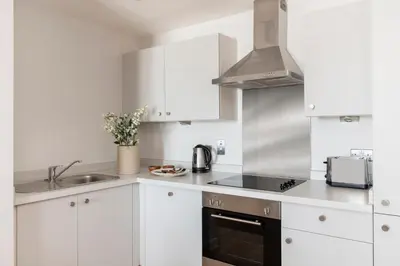 a white kitchen with a sink and a stove at Cove Paradise Street in Liverpool
