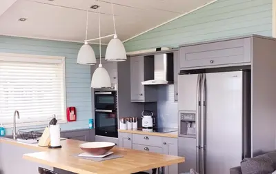a kitchen with a refrigerator and a wooden table at Fenna Lakeside Lodge - Pine Lake Resort in Carnforth