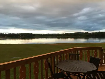 a table and chairs on a deck with a view of a lake at Fenna Lakeside Lodge - Pine Lake Resort in Carnforth
