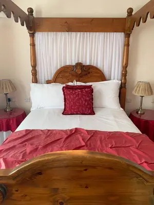 a wooden bed with a red pillow on it at The Old Coach House in Blackpool