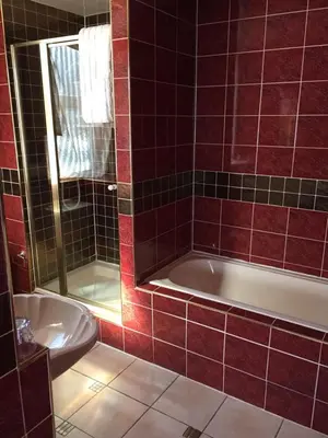 a red tiled bathroom with a tub and a sink at The Old Coach House in Blackpool