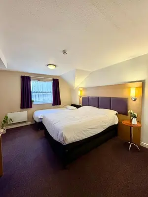 a hotel room with two beds and a window at Premier Nights, Wigan, Standish M6 J27 in Standish