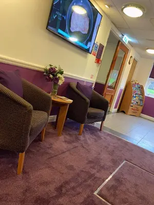 a waiting room with chairs and a table and a tv at Purple Roomz Preston South in Preston