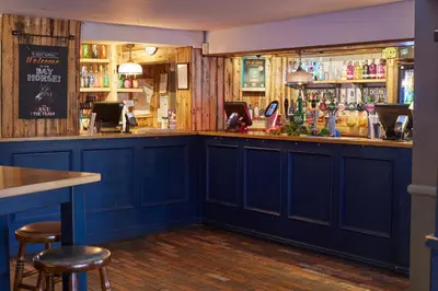 a bar with blue cabinets and bar stools at The Bay Horse Hotel in Haydock