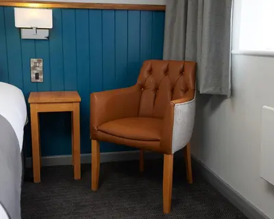 a brown chair sitting in a room next to a table at The Bay Horse Hotel in Haydock