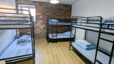 a room with three bunk beds and a brick wall at International Inn in Liverpool