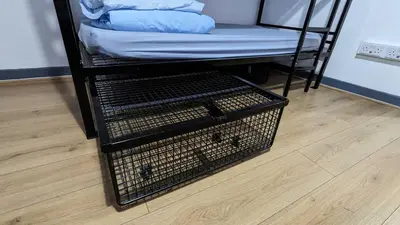 a cage with a mattress and a bed on a wooden floor at International Inn in Liverpool