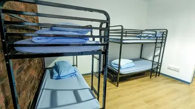 a room with three bunk beds and a brick wall at International Inn in Liverpool