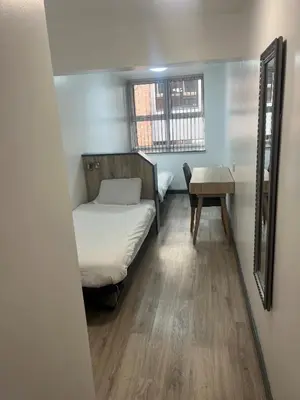 a small room with a bed and a table at International Inn in Liverpool