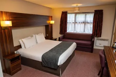 a hotel room with a bed and a chair at The Fernhurst by Greene King Inns in Blackburn