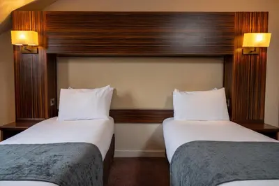 a hotel room with two beds and two lamps at The Fernhurst by Greene King Inns in Blackburn