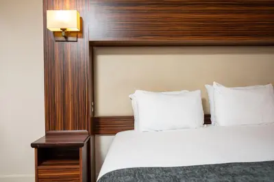 a bedroom with a large bed with a wooden headboard at The Fernhurst by Greene King Inns in Blackburn