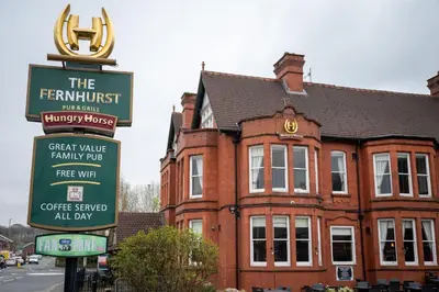 a sign in front of a red brick building at The Fernhurst by Greene King Inns in Blackburn