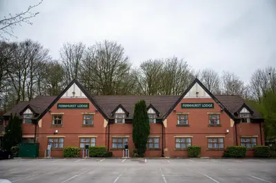 a large red brick building with trees in the background at The Fernhurst by Greene King Inns in Blackburn