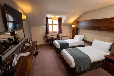 a hotel room with two beds and a table at The Fernhurst by Greene King Inns in Blackburn