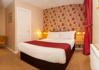 a hotel room with a large bed with a red curtain at The Lawton in Blackpool