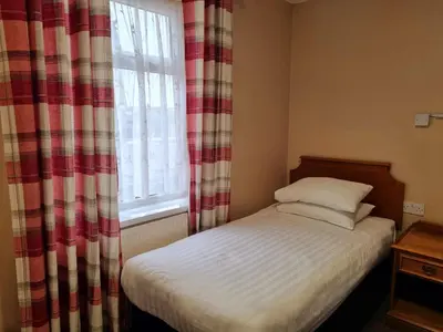 a small bed in a room with a window at The Beechfield Hotel in Blackpool