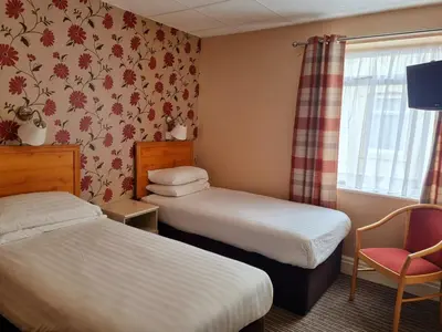 a hotel room with two beds and a chair at The Beechfield Hotel in Blackpool
