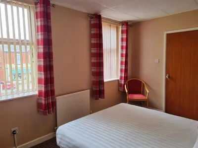 a bedroom with a bed and a window and a chair at The Beechfield Hotel in Blackpool