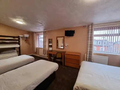 a room with two beds and a desk with a mirror at The Beechfield Hotel in Blackpool