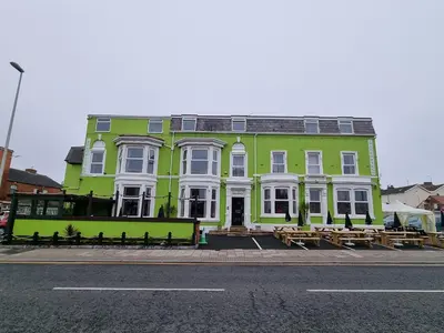 a green and white building with picnic tables in front of it at The Beechfield Hotel in Blackpool