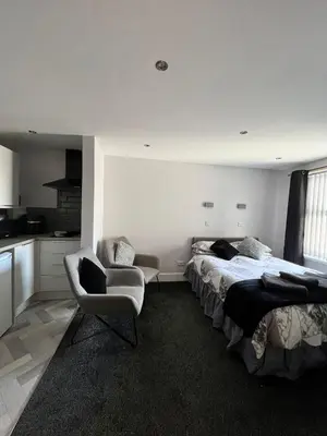 a bedroom with a bed and a couch and a chair at St Nicholas Holiday Apartments in Blackpool