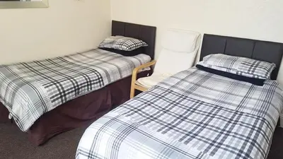 a room with two twin beds and a chair at St Nicholas Holiday Apartments in Blackpool