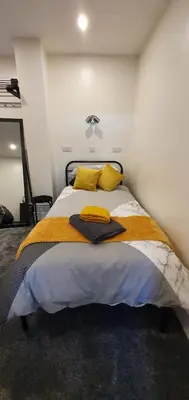 a bedroom with a large bed with yellow pillows at St Nicholas Holiday Apartments in Blackpool