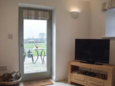 a living room with a tv and a door to a patio at Five Barred Gate Barn in Inglewhite