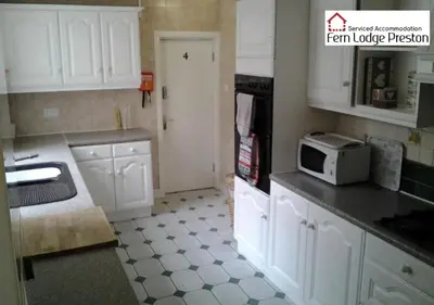 a kitchen with white cabinets and a microwave at 4 Bedroom House at Fern Lodge Preston Serviced Accommodation - Free WiFi & Parking in Preston